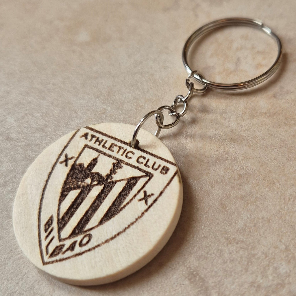 Llavero artesanal fabricado en madera natural, cortado y grabado mediante tecnología láser de alta precisión.

Presenta un diseño circular de acabado suave, con grabado permanente de gran definición que resalta el escudo del Athletic Club de Bilbao con un contraste elegante y duradero.

Incluye resistente aro metálico con cadena, ideal para llaves, mochilas...

Gracias a su ligereza y estilo natural, es perfecto como regalo personalizado o detalle ecológico.

Grabado a doble cara.

¡Contacta con nosotros pa