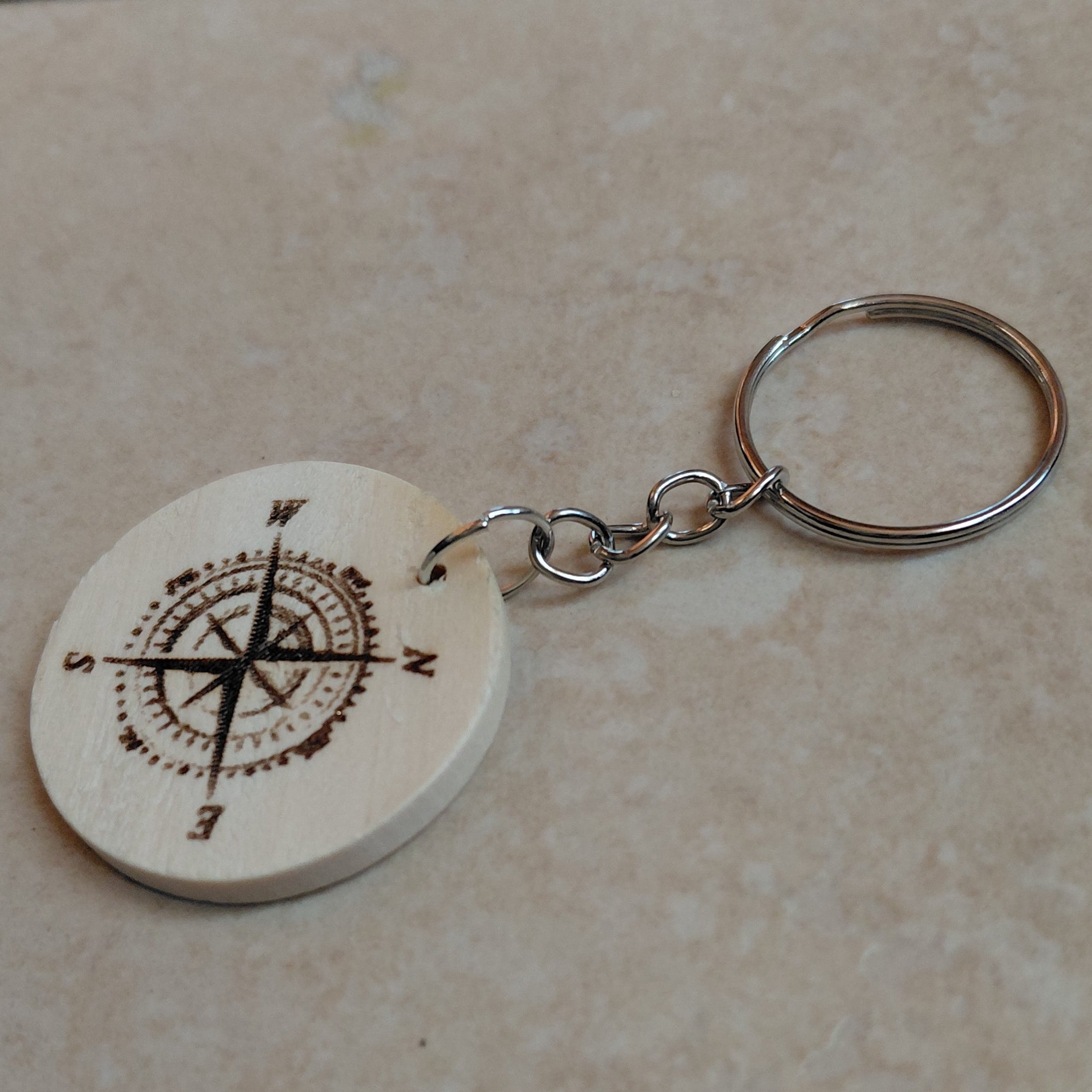Llavero artesanal de madera grabado láser redondo con la imagen de na brujula, ideal para regalar a excursionistas