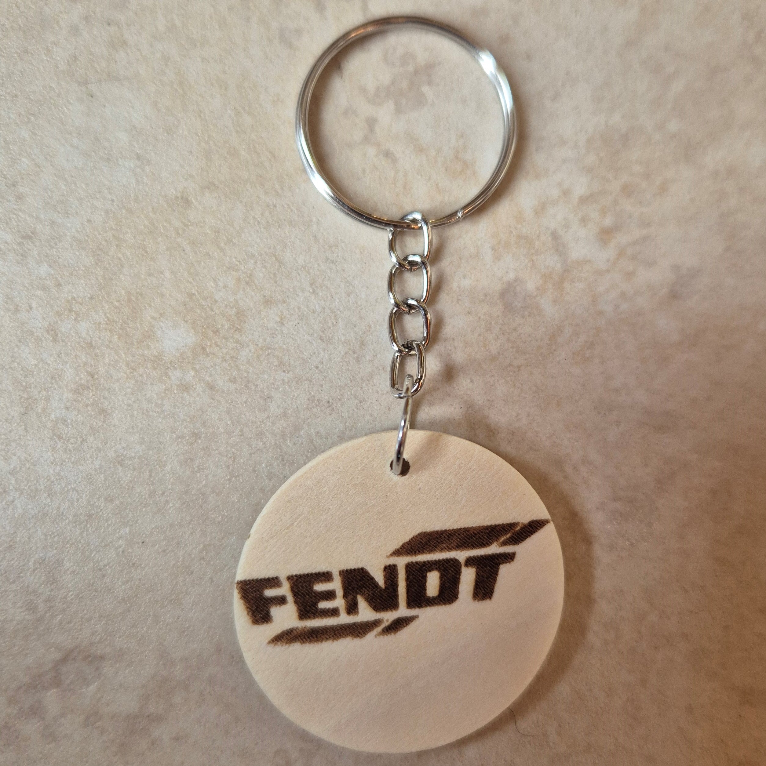 Llavero artesanal fabricado en madera natural, cortado y grabado mediante tecnología láser de alta precisión.

Presenta un diseño circular de acabado suave, con grabado permanente de gran definición que resalta el logotipo de la marca de tractores Fendt con un contraste elegante y duradero.

Incluye resistente aro metálico con cadena, ideal para llaves, mochilas...

Gracias a su ligereza y estilo natural, es perfecto como regalo personalizado o detalle ecológico.