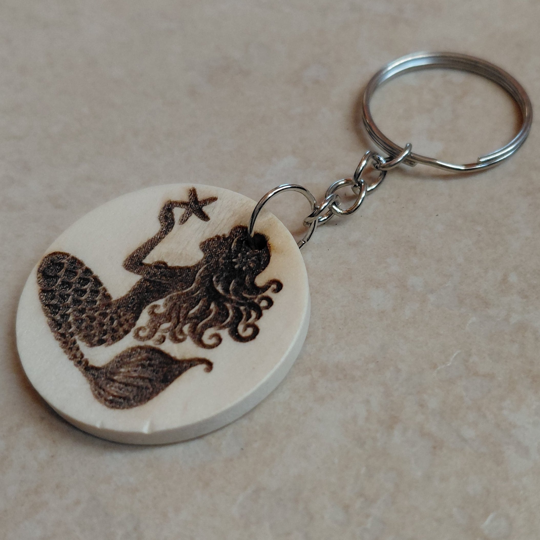 Llavero artesano de madera grabado a láser con la imagen de una preciosa sirena con una estrella de mar en las manos