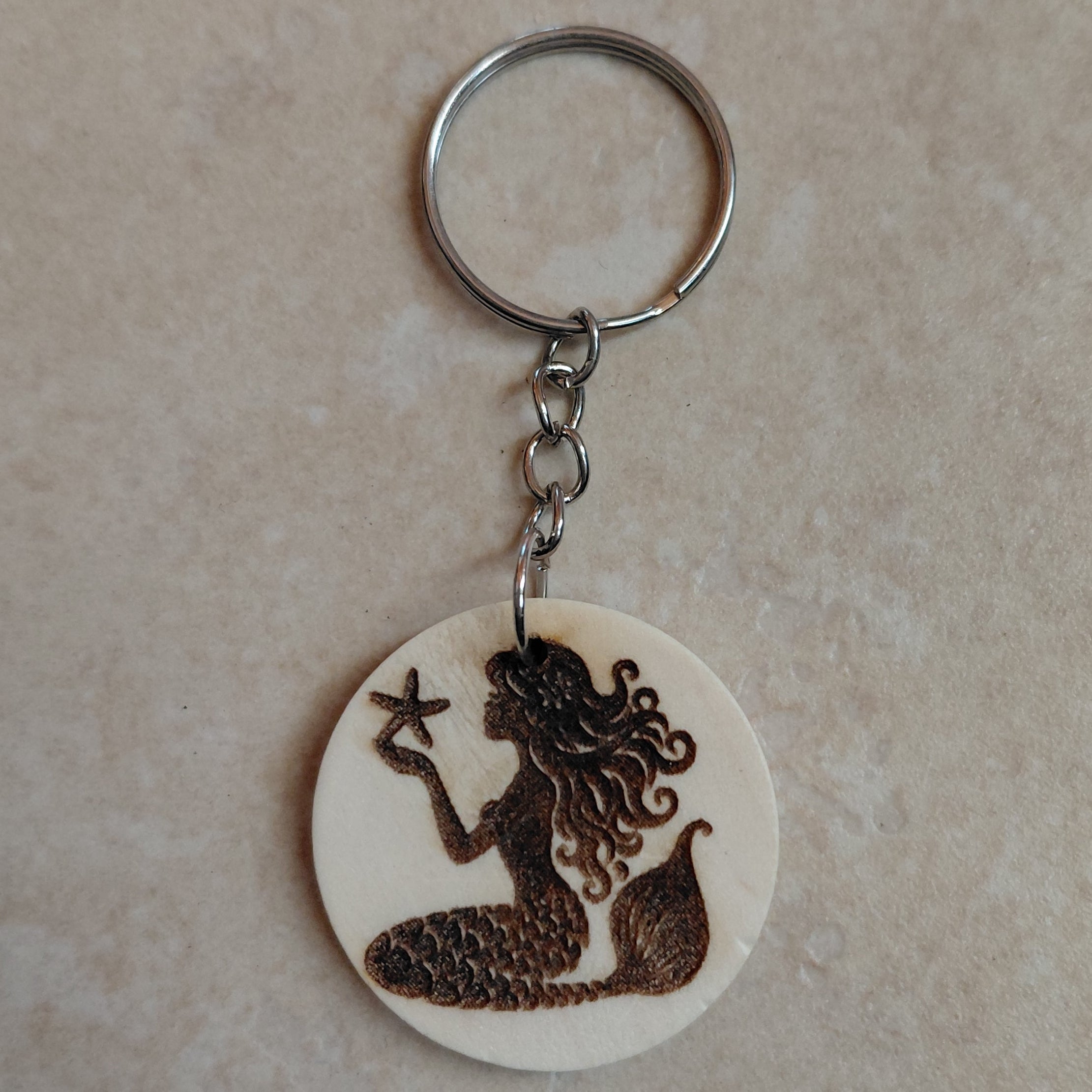Llavero artesano de madera grabado a láser con la imagen de una preciosa sirena con una estrella de mar en las manos