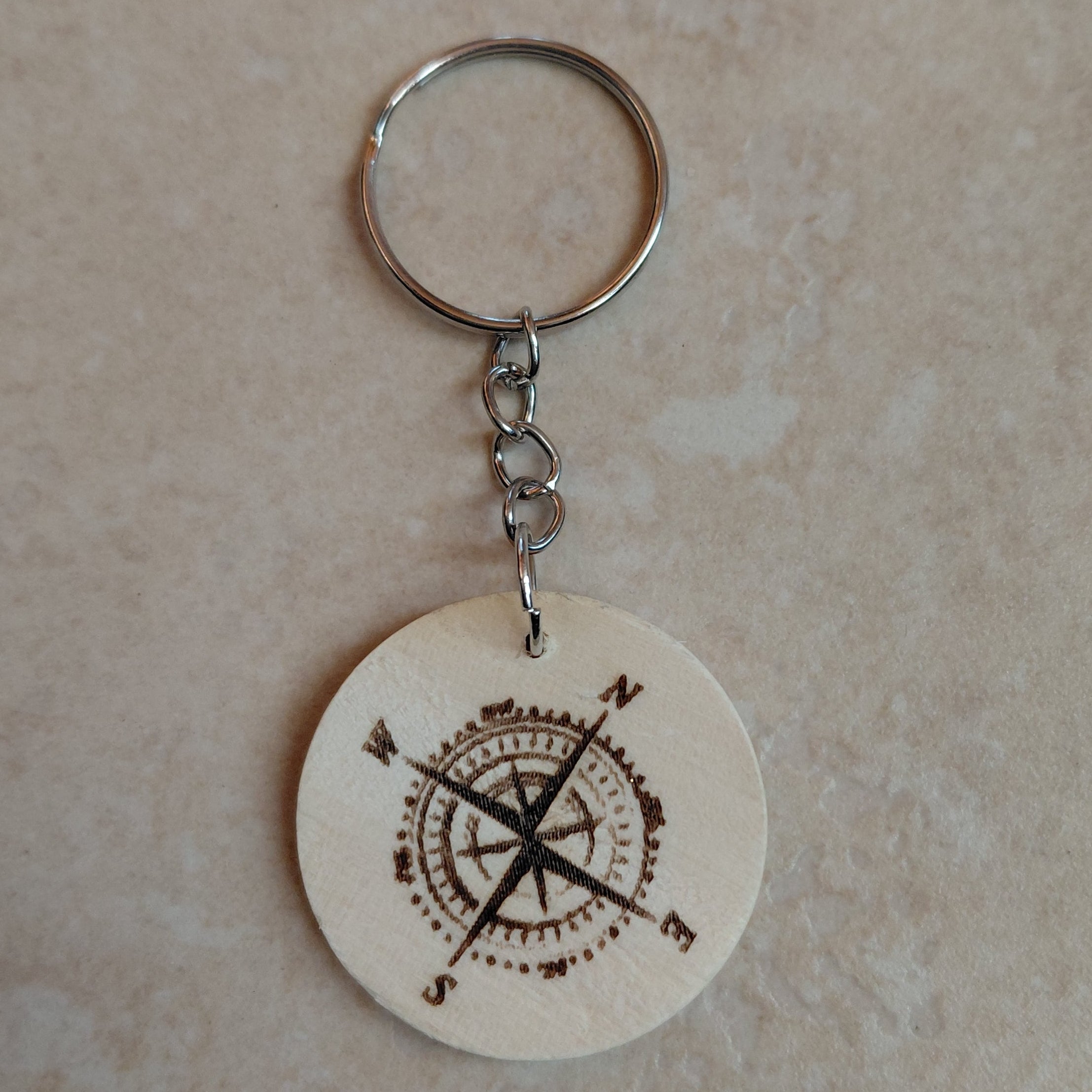 Llavero artesanal de madera grabado láser redondo con la imagen de na brujula, ideal para regalar a excursionistas