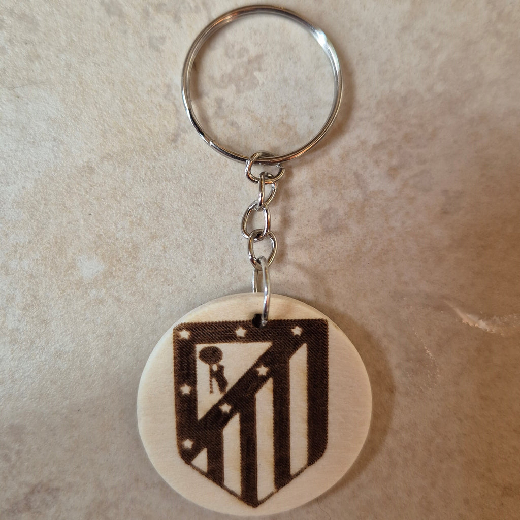 Llavero artesanal fabricado en madera natural, cortado y grabado mediante tecnología láser de alta precisión.

Presenta un diseño circular de acabado suave, con grabado permanente de gran definición que resalta el escudo del Atlético de Madrid con un contraste elegante y duradero.

Incluye resistente aro metálico con cadena, ideal para llaves, mochilas...

Gracias a su ligereza y estilo natural, es perfecto como regalo personalizado o detalle ecológico.

Grabado a doble cara.

¡Contacta con nosotros para pe
