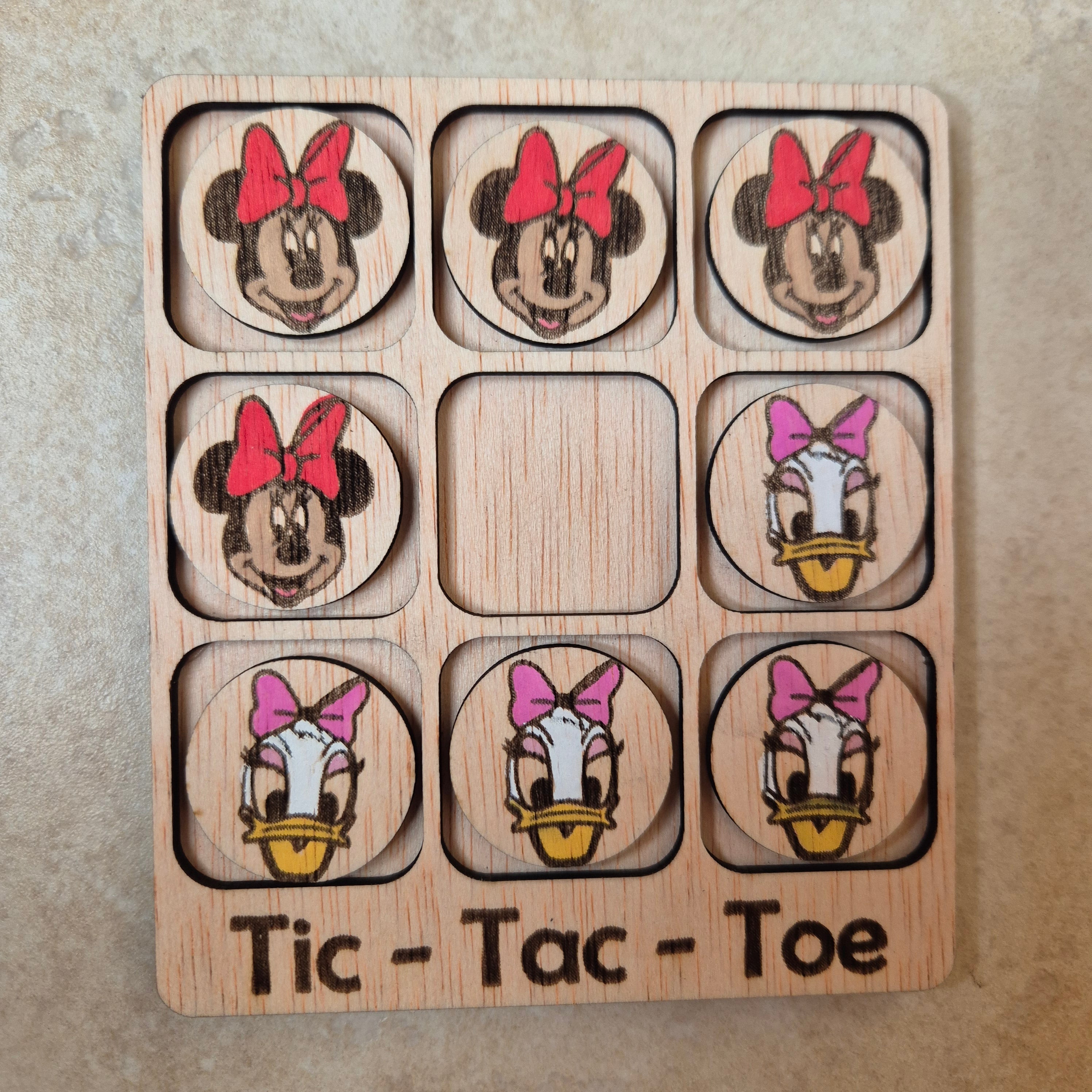Hermoso juego de Tic-Tac-Toe (Tres en raya) artesanal, elaborado en madera natural mediante técnica de corte y grabado láser, y pintado completamente a mano con gran detalle y cuidado.

Incluye fichas ilustradas con los famosos personajes de Disney (Minnie y Daisy), lo que lo convierte en un artículo único, colorido y lleno de encanto, ideal tanto para jugar como para decorar.

Perfecto como regalo original, recuerdo artesanal o elemento decorativo para habitaciones infantiles, escritorios o estanterías.